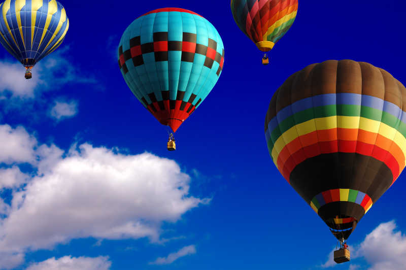 在蓝天白云天空中飞行的各色热气球