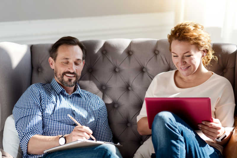 夫妇坐在沙发上使用笔记本电脑做笔记