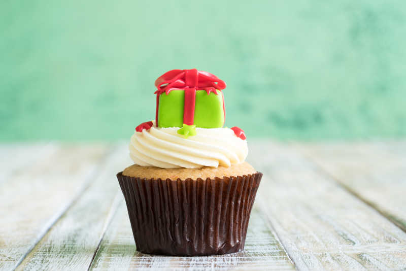 淡绿色背景下木桌上的圣诞节小蛋糕