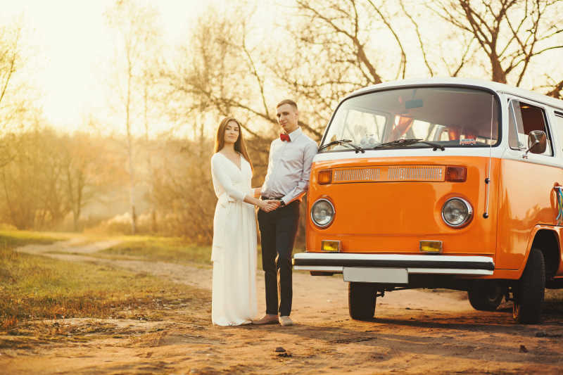 日落时分站在橙色面包车旁的情侣