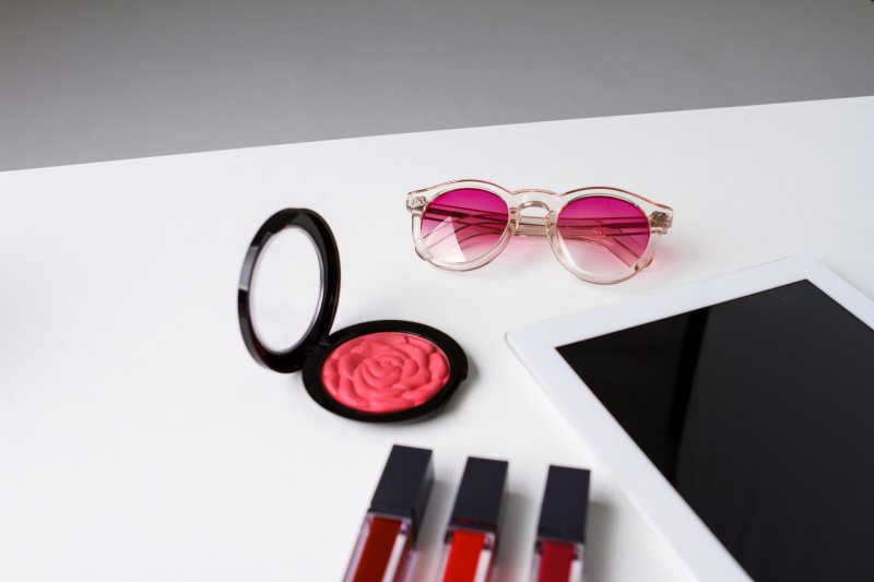 白色背景下的口红和粉红色眼镜