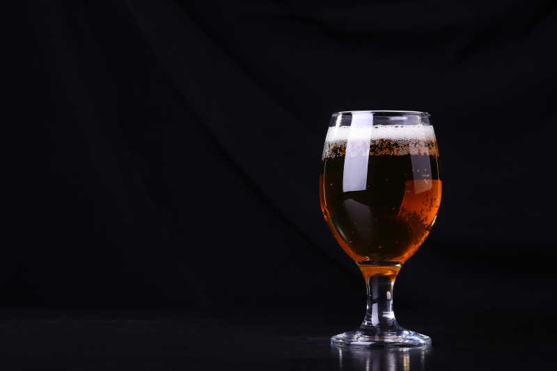 黑色背景下装满啤酒的玻璃杯