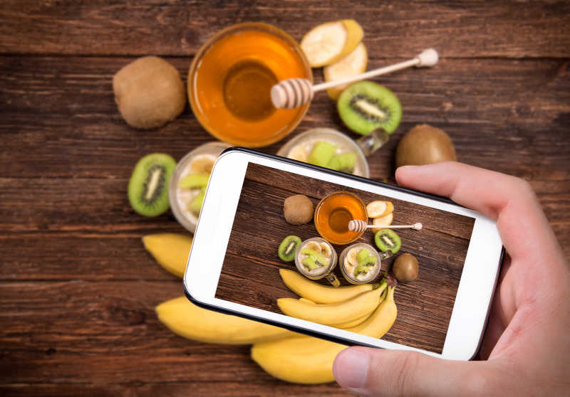 手拍照香蕉和蜂蜜与智能手机