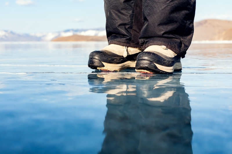 透明冰中的穿着防滑靴的人脚