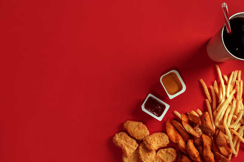 红色背景下薯条鸡块和饮料