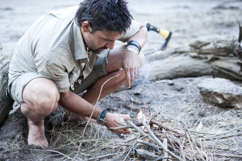 用打火机点树枝的男人
