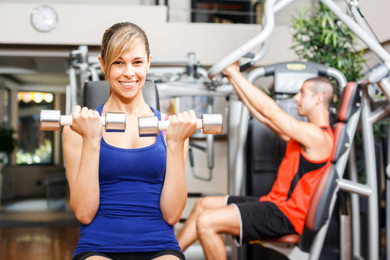 健身房内使用哑铃健身的女人