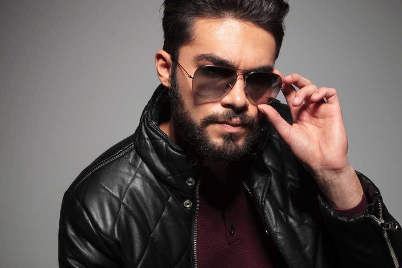 灰色背景下长胡子戴着太阳镜的男子