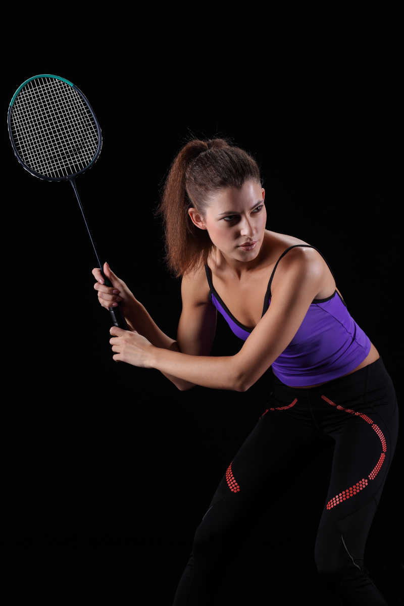 黑色背景下羽毛球运动的女人