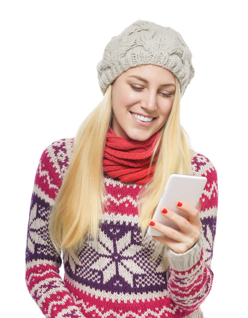 带着灰色帽子的年轻金发女孩穿着红色毛衣围巾手拿手机