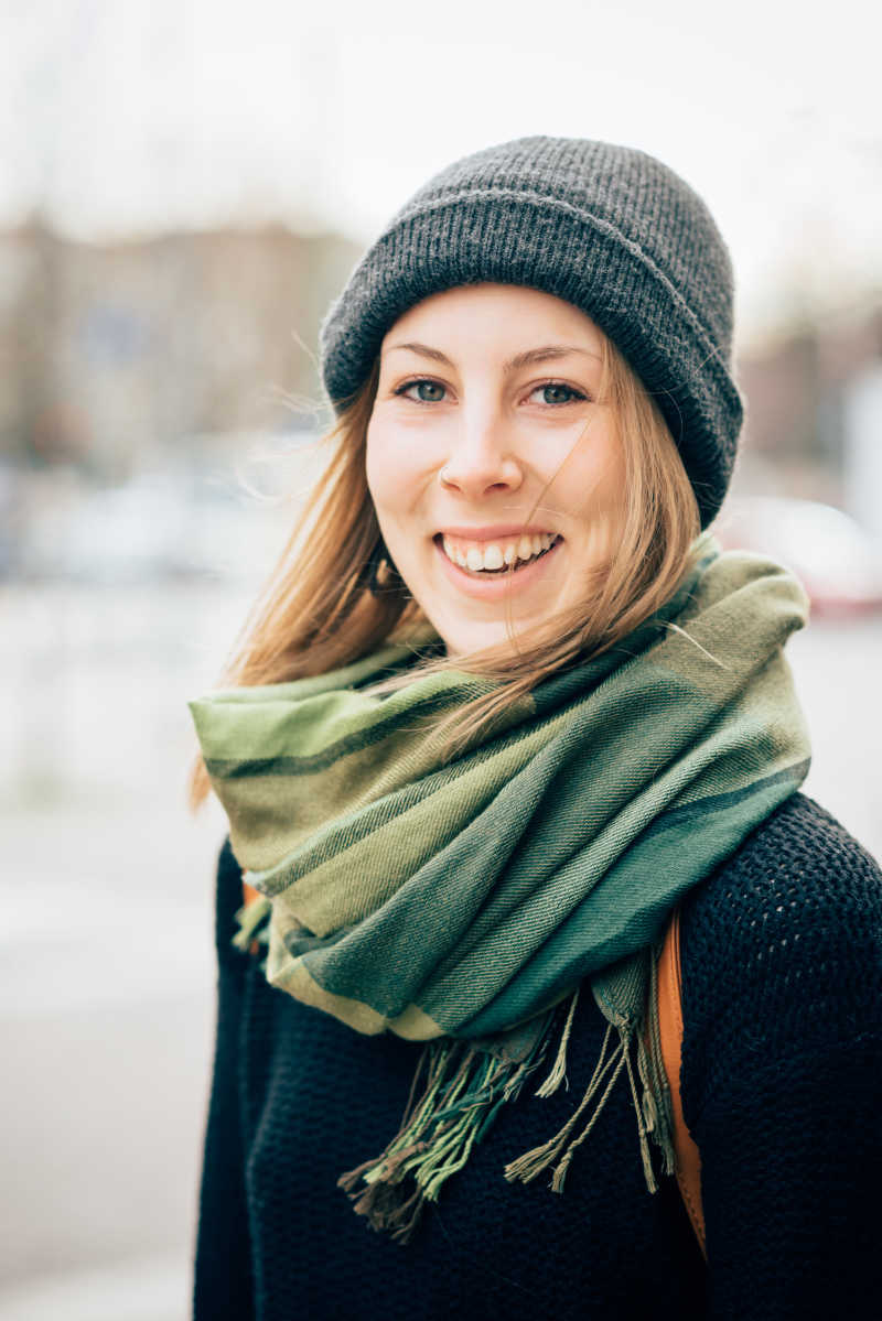 戴着围巾帽子和黑色毛衣的金发女人