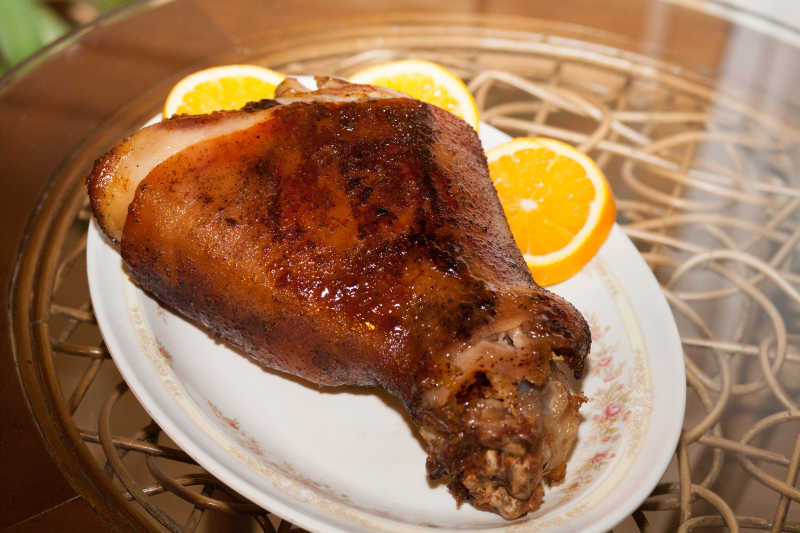 白色盘子中的烤猪肘和橙子片