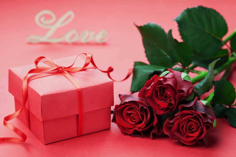 情人节粉红色背景下的礼品盒和红玫瑰