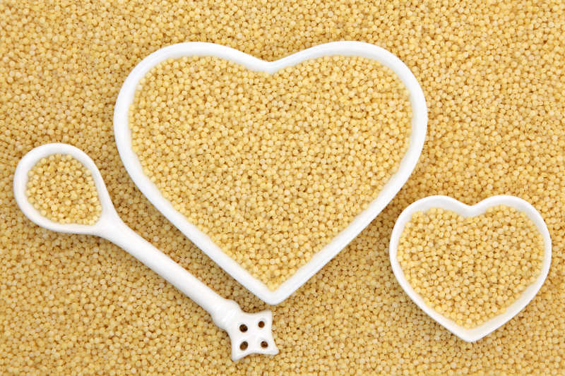 在心形碗和瓷勺形成背景珍珠库斯库斯食品