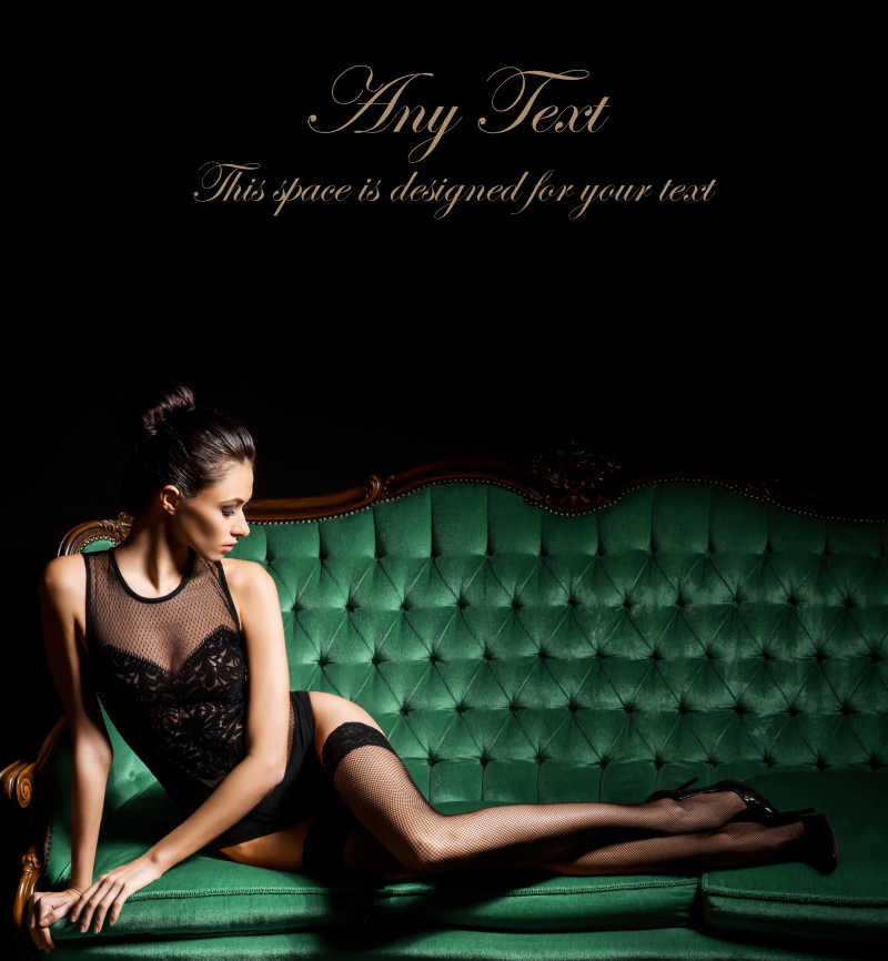 穿着性感内衣和袜子的女人摆在绿色沙发在老式内饰