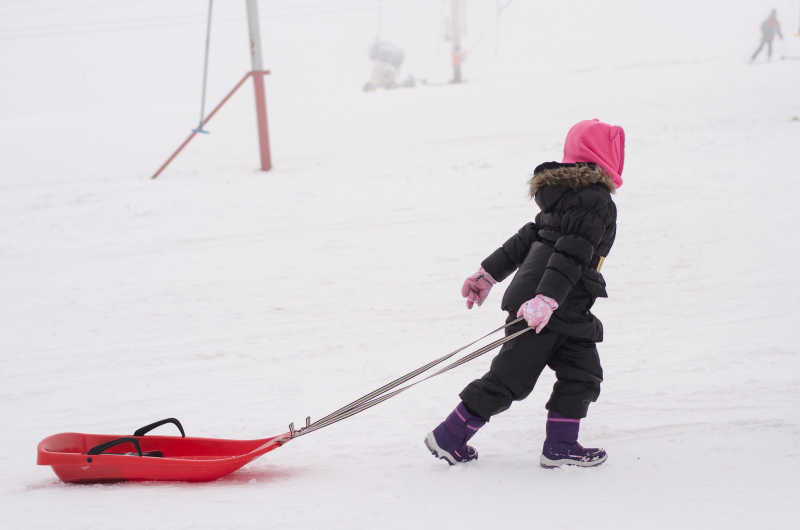 孩子拉着雪橇在雪地里