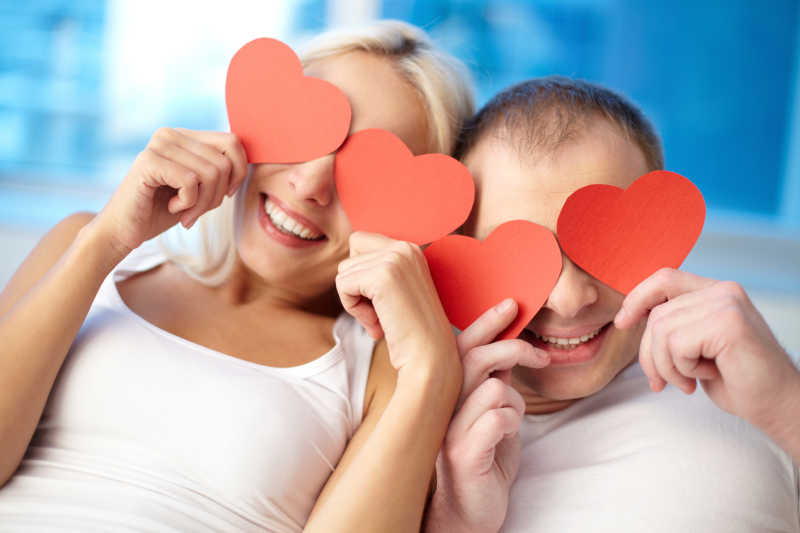 一对幸福夫妇用红心纸挡着眼睛的画像
