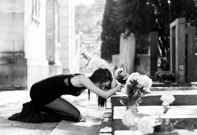 坟墓前的悲痛中跪地的女人