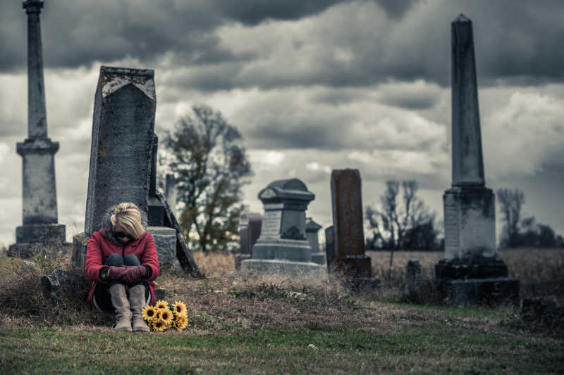 在墓碑前的孤独忧郁的年轻女子