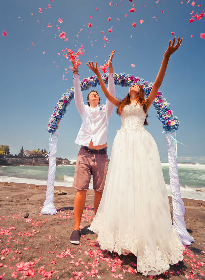 新婚夫妇在双手向上扬起花瓣