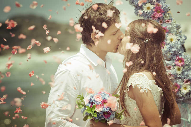 幸福的新婚夫妇在花瓣雨中亲吻