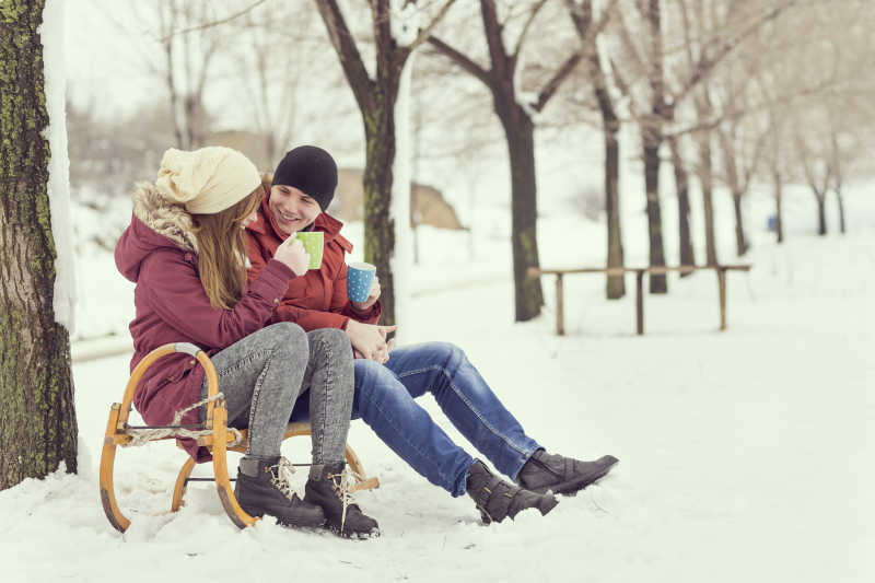 冬季一对情侣坐在路边的椅子上