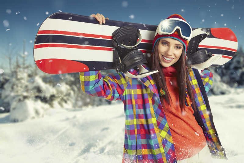 性感的美女扛着滑雪板微笑