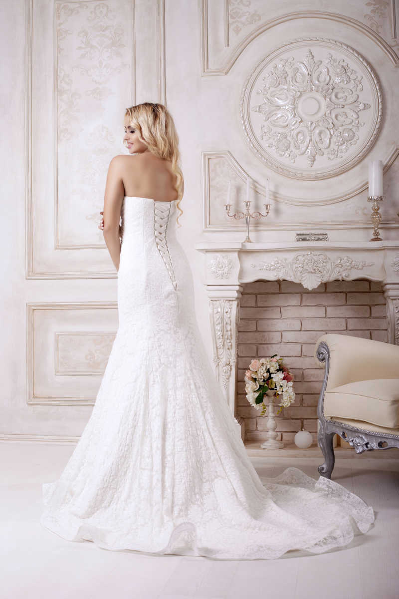 室内的壁炉旁边穿着婚纱的美女的背影