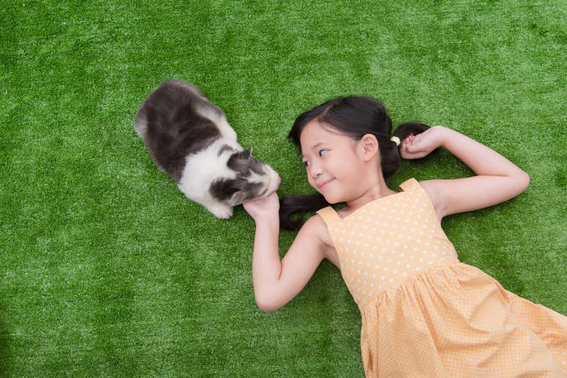 可爱的女孩和她的小狗躺在草地上玩耍