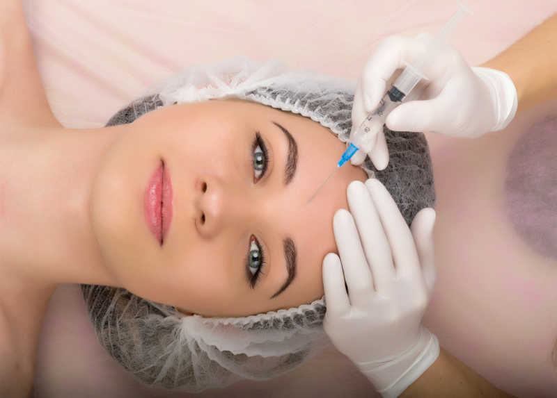 躺在床上在额头打美容针的美女