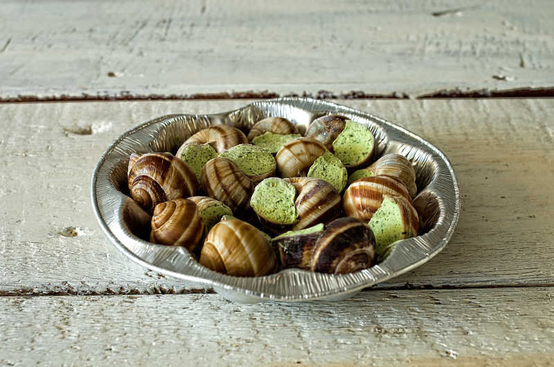 旧餐桌上金属托盘上的勃艮第蜗牛