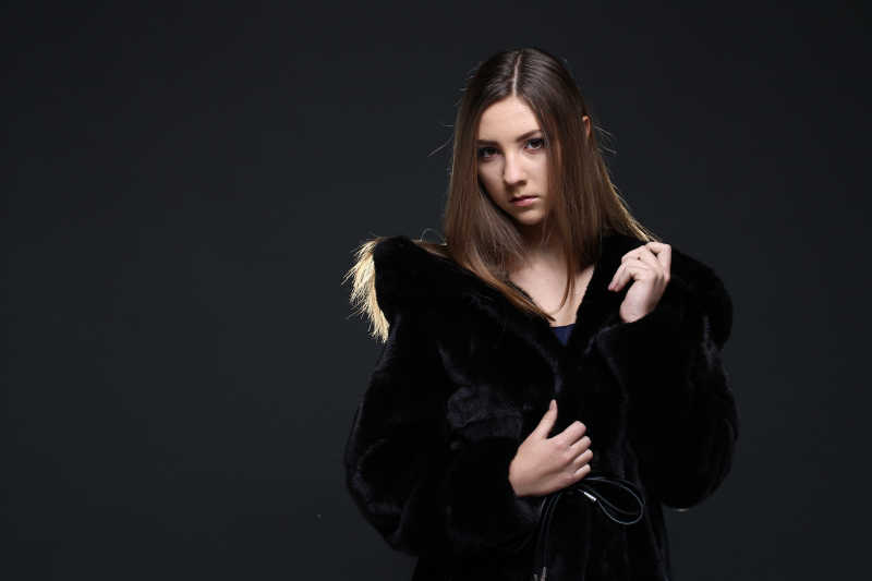 黑色背景下穿裘皮大衣的美女女人