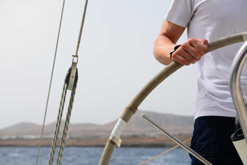 帆船上握着船舵的船长