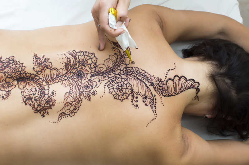 在美容院做背部纹身的人