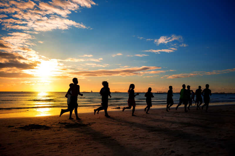 一群年轻人在美丽的夏天在海滩上跑步