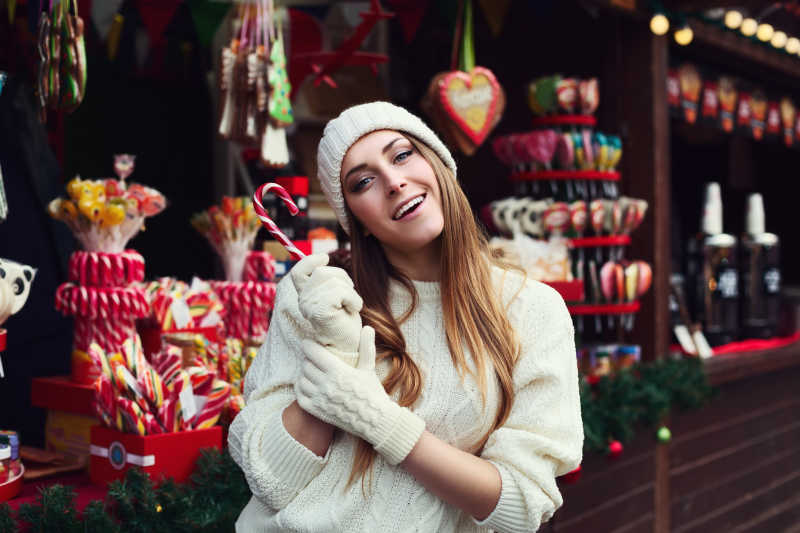 微笑的年轻漂亮的女人拿着棒棒糖