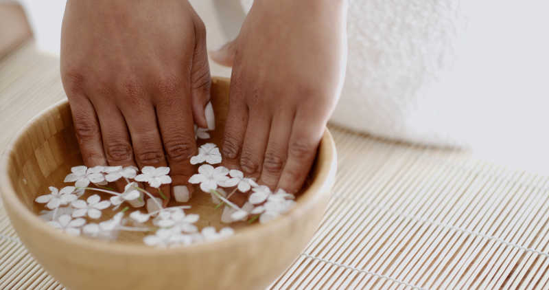 女人将手泡在有花瓣的水里