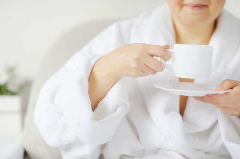 面带微笑的女人穿着白大褂坐在桌旁喝着热饮