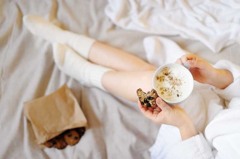 漂亮女孩喝热饮料吃饼干
