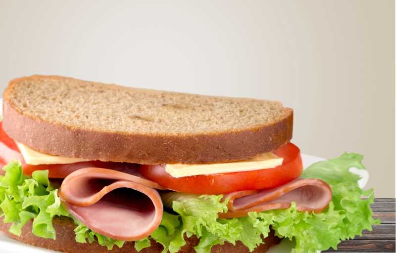 浅色背景下的木色桌上的三明治