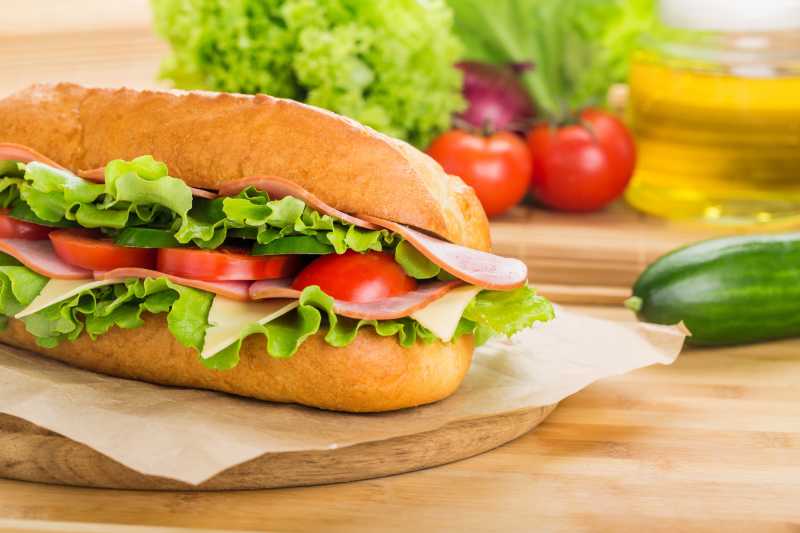 木色桌上的三明治和蔬菜