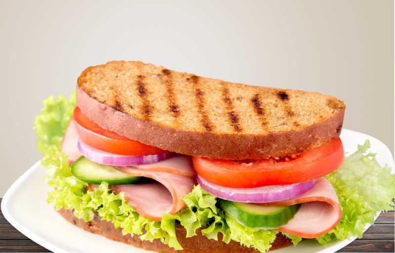 淡黄色背景下白色盘子里的三明治