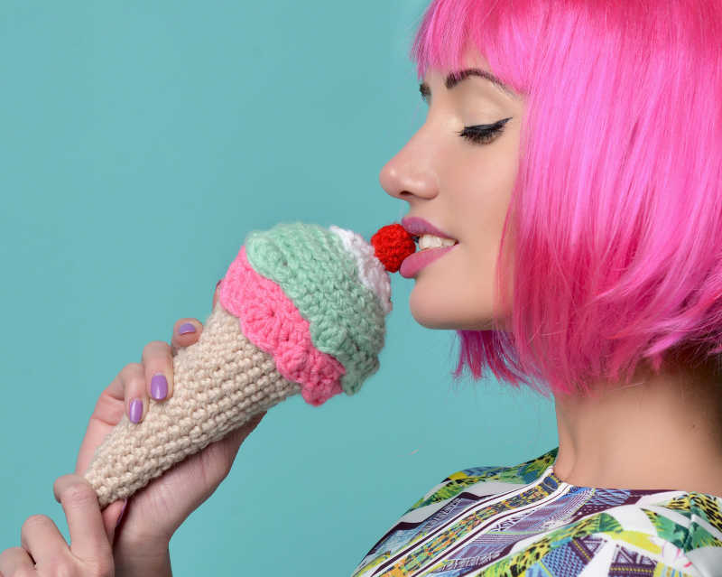 薄荷绿背景下的打扮时髦的女人拿着冰激凌