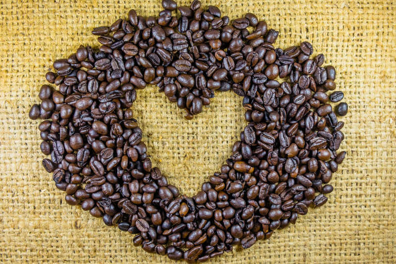 黄色亚麻布上咖啡豆摆出的心形造型