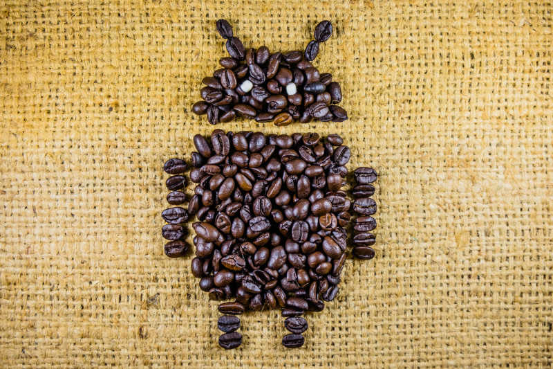 黄色亚麻布上咖啡豆组成的安卓机器人造型