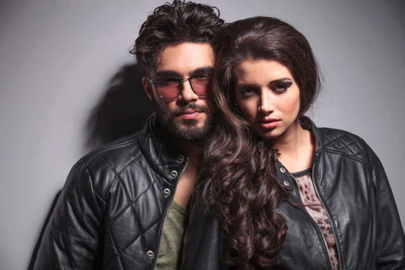 年轻的时尚夫妇在灰色的墙上