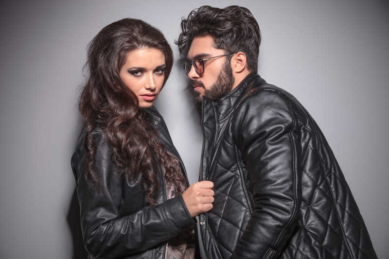 漂亮的时尚女人一边看镜头一边拉着男友的外套