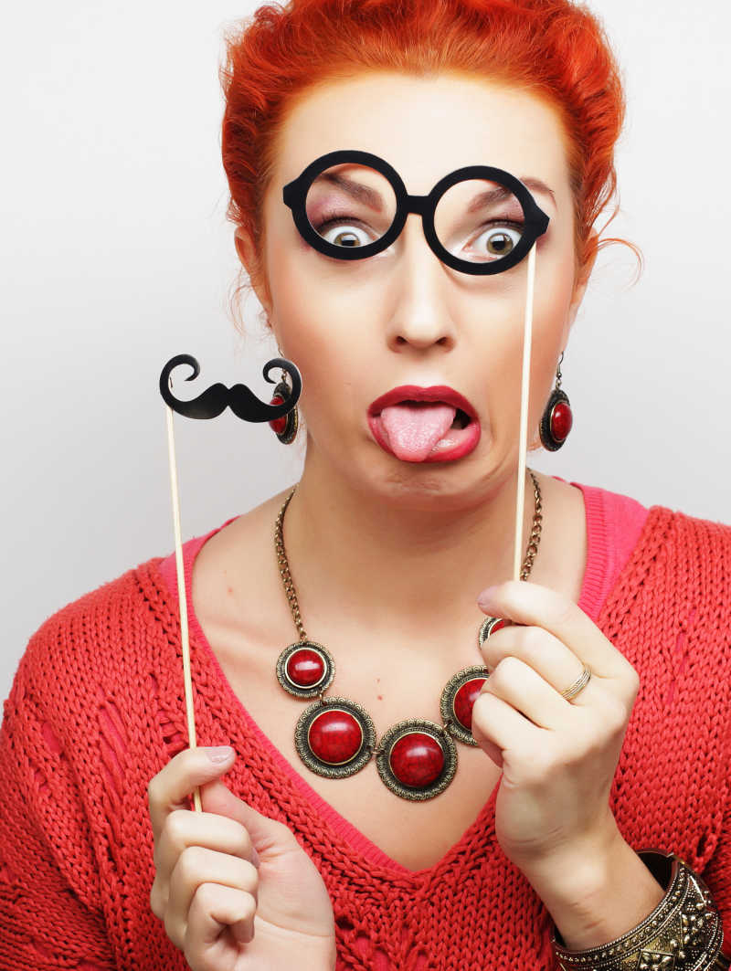 拿着胡子和眼镜道具的年轻女人