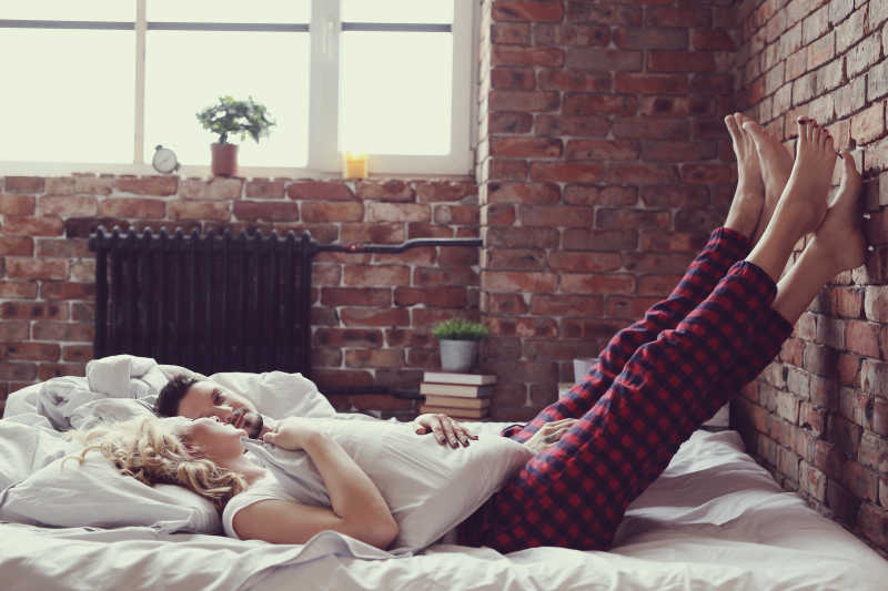 年轻夫妇穿着情侣装躺在床上深情对视