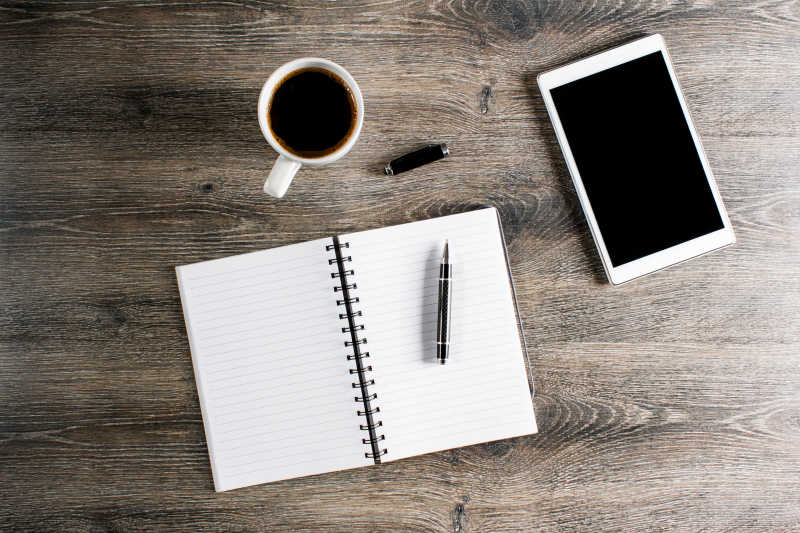 桌上的咖啡与笔记簿与电子产品